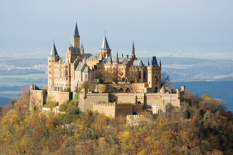 Burg Hohenzollern mit zahlreichen Türmen auf dem Gipfel des Zollerbergs, umgeben von herbstlich gefärbtem Wald
