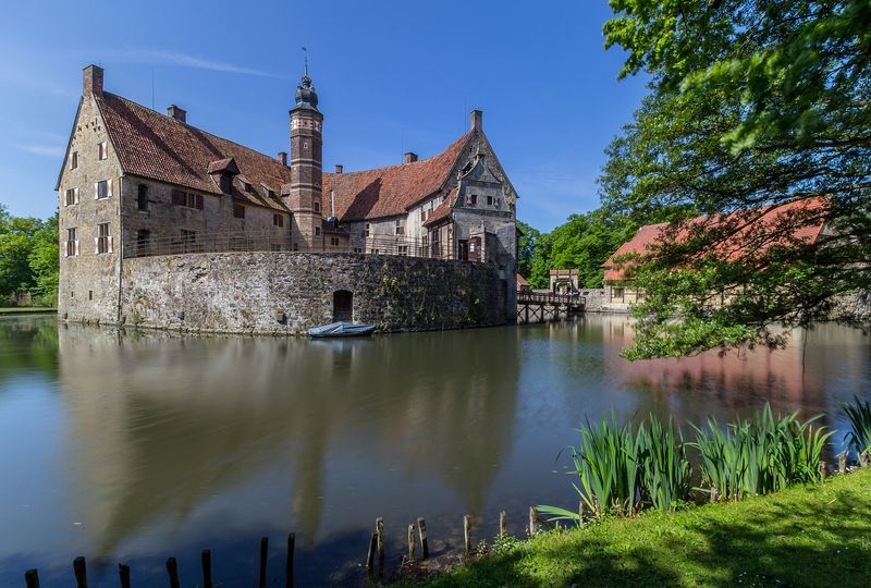 Die Wasserburg Vischering mit Backsteinturm und Bruchsteinmauern, die sich in der Gräfte spiegelt