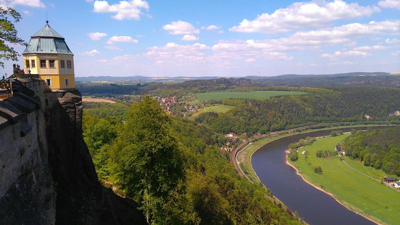 Die Friedrichsburg auf der Felskante der Festung Königstein, darunter das grüne Elbtal mit dem Fluss und der Bahnlinie