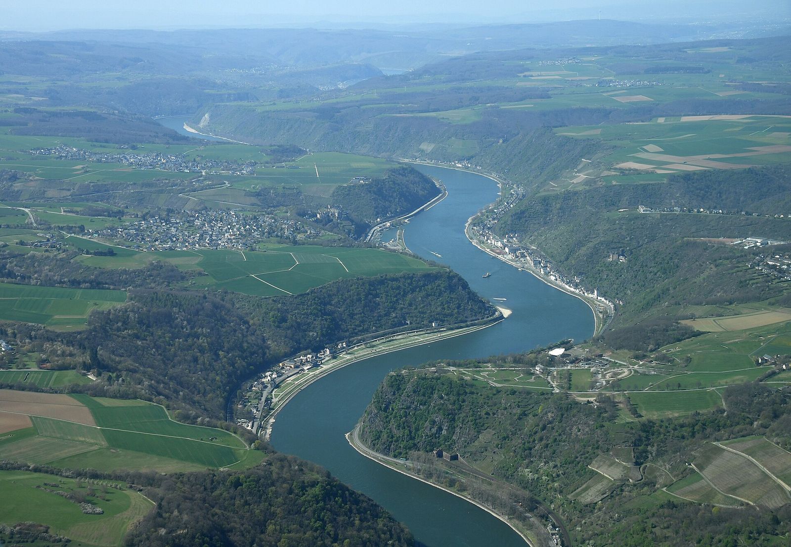 Luftbild des Oberen Mittelrheintals: Der Rhein windet sich zwischen bewaldeten Hängen, unten rechts der Loreley-Felsen