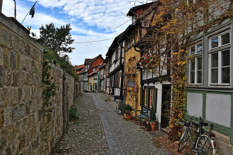 Kopfsteinpflastergasse mit Fachwerkhäusern und Bruchsteinmauer am Schlossberg in Quedlinburg
