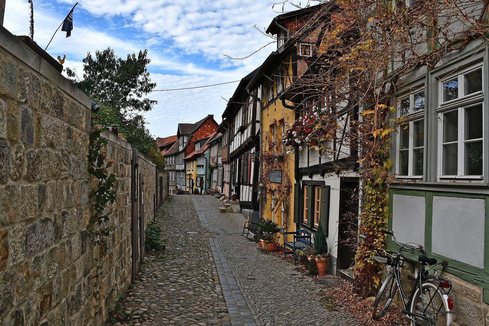 Kopfsteinpflastergasse mit Fachwerkhäusern und Bruchsteinmauer am Schlossberg in Quedlinburg